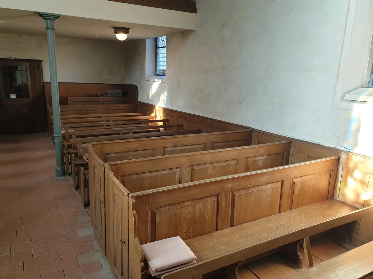 Man sieht Kirchenbänke in einer Kirche.